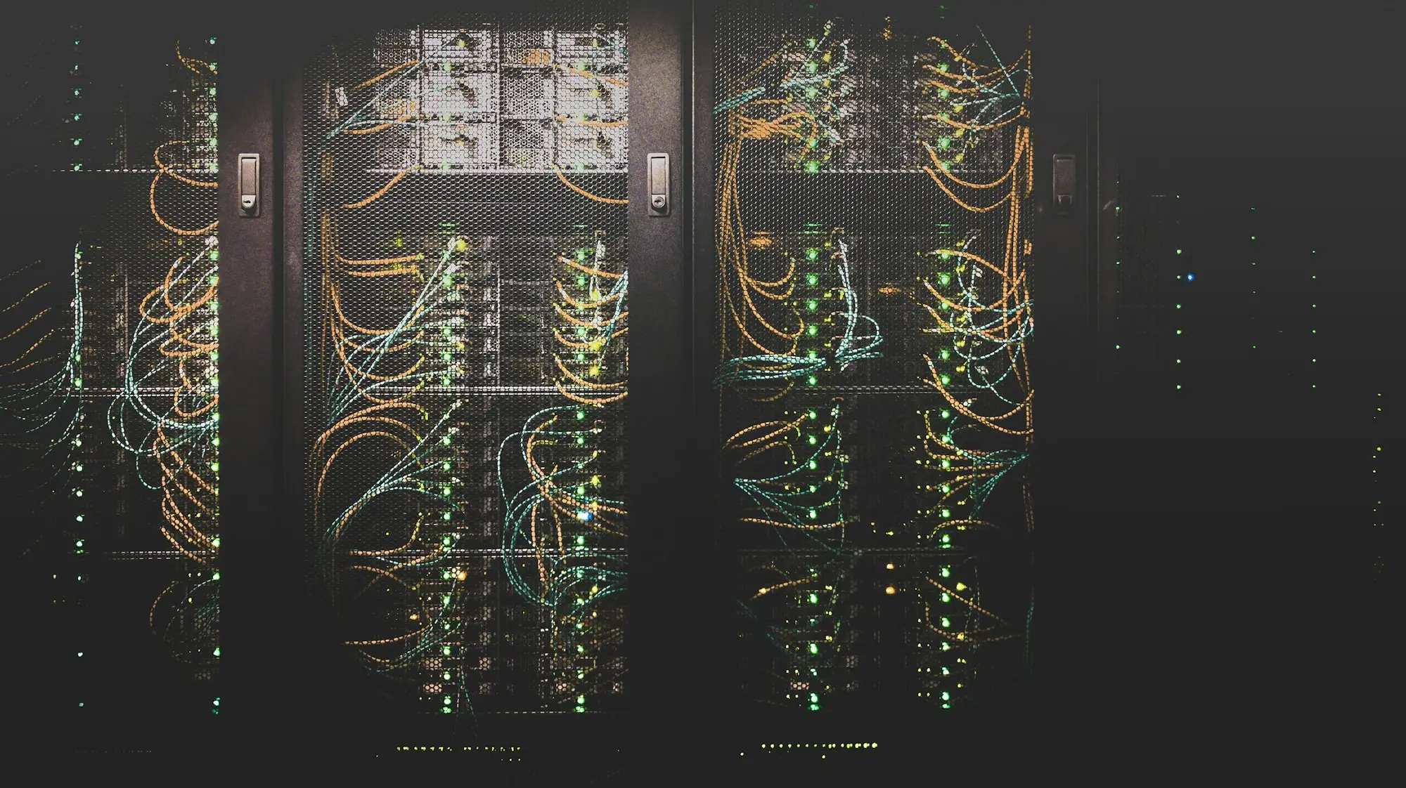 Baies de serveurs câblées, voyants allumés dans la pénombre d'un local technique